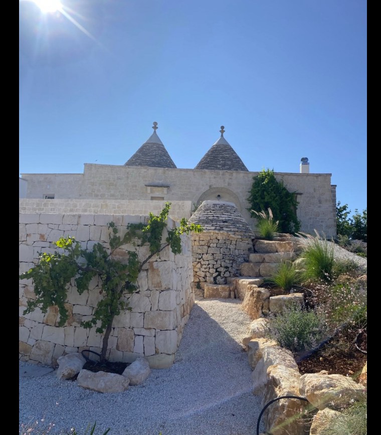 Il sentiero tra i muretti a secco che porta all'ingresso di un trullo